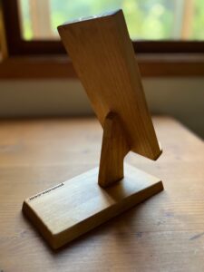 窓際の机の上の木製スマホスタンド　斜め右後ろ