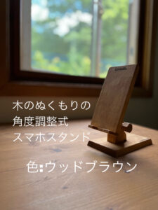 窓際の机の上の木製スマホスタンド