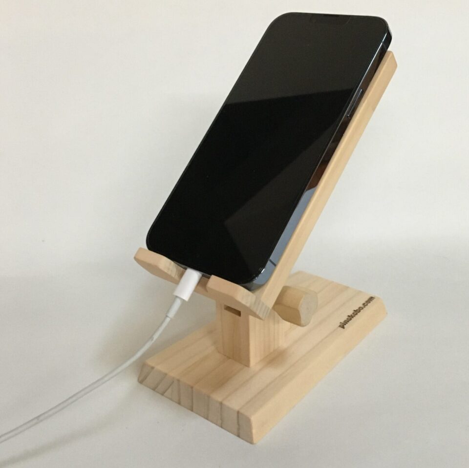 木製スマホスタンドに載っているスマートフォンは充電中