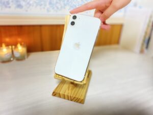 木製スマホスタンドに乗せたiphoneと女性の手