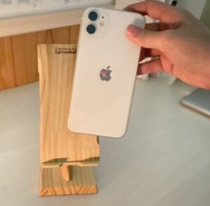 木製スマホスタンドにスマホを載せようとしている女性の手